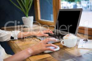 Cropped image of woman using laptop in careteria