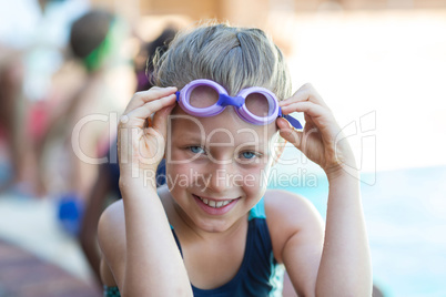 Smiling little girl holding swimming goggles