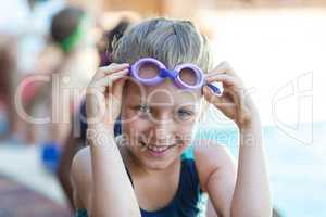 Smiling little girl holding swimming goggles