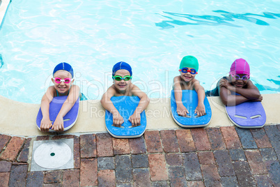 Little swimmers with kickboards at poolside