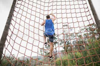 Man climbing a net during obstacle course