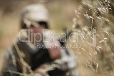 Military soldier hiding in grass while guarding