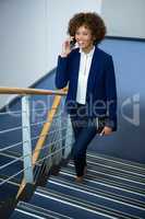 Businesswoman talking on mobile phone while climbing steps
