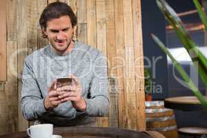 Man using smart phone at table in coffee shop