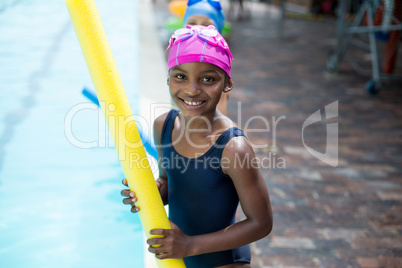 Girl holding pool noodle at poolside