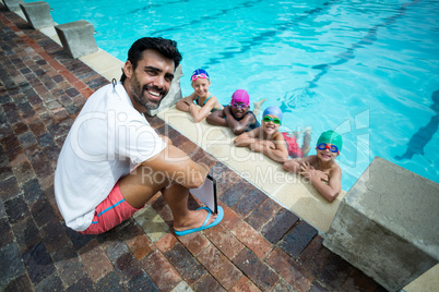 Happy male trainer with little swimmers at poolside