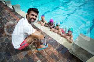 Happy male trainer with little swimmers at poolside