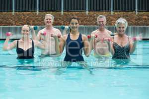 Trainer and senior swimmers weightlifting in swimming pool