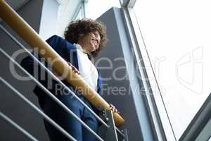 Businesswoman leaning over the railing of staircase