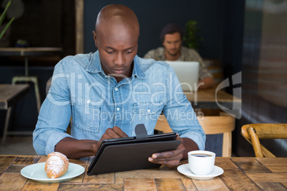 Man using tablet computer at table in coffee shop