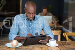 Man using tablet computer at table in coffee shop