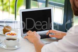 Businessman using laptop at table in restaurant
