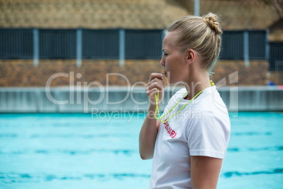 Female lifeguard whistling at poolside