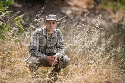 Portrait of military soldier crouching in grass