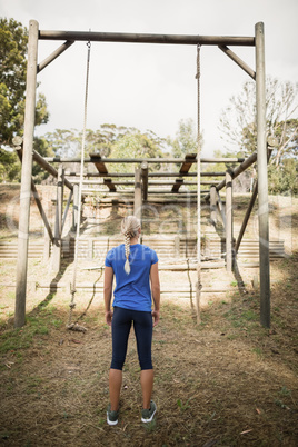 Rear view of fit woman looking at rope during obstacle course