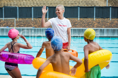 Lifeguard instructing children at poolside