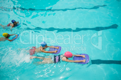 Girls and boys using kickboard while swimming in pool