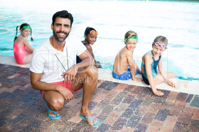 Happy male instructor and students at poolside