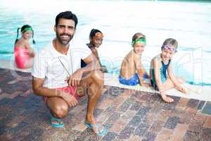 Happy male instructor and students at poolside