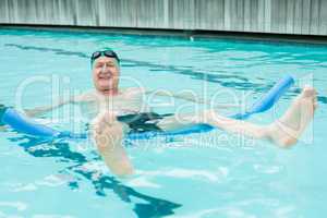 Cheerful mature man swimming with pool noodle