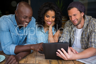Happy friends using digital tablet in coffee house