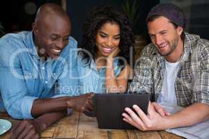 Happy friends using digital tablet in coffee house