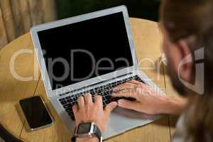 High angle view of man using laptop in coffee shop