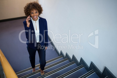 Businesswoman talking on mobile phone while walking upstairs