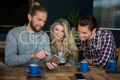 Man showing smart phone to friends at table in coffee shop