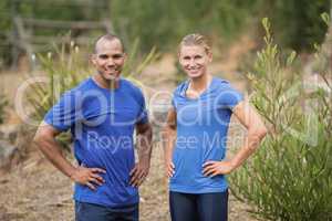 Fit man and woman standing with hands on hip during boot camp training