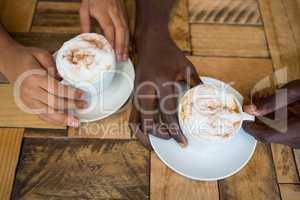 Couple hands holding coffee cups in cafe