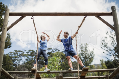 Fit man and woman giving high five during obstacle course