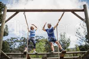 Fit man and woman giving high five during obstacle course