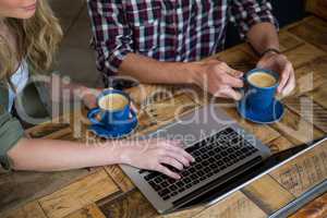 Couple using laptop while having coffee in cafeteria