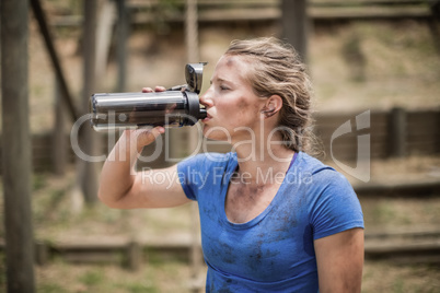 Woman drinking water from bottle during obstacle course