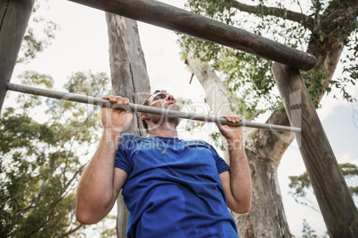Fit man performing pull-ups on bar during obstacle course