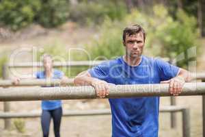 Tired man and woman leaning on a hurdle during obstacle course