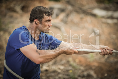 Man playing tug of war during obstacle course