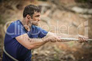 Man playing tug of war during obstacle course