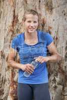 Tired woman holding water bottle during obstacle course
