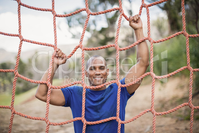 Smiling fit man climbing a net during obstacle course