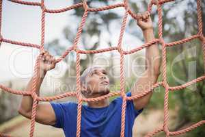 Fit man climbing a net during obstacle course