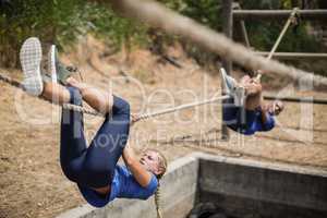 Fit man and woman crossing the rope during obstacle course