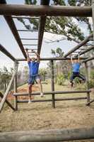 Fit man and woman climbing monkey bars during obstacle course