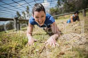 Fit woman crawling under the net during obstacle course