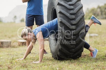 Woman crawling through the tire during obstacle course