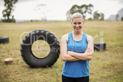 Fit woman standing with arms crossed in boot camp