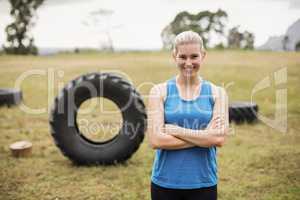 Fit woman standing with arms crossed in boot camp