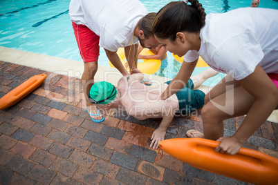 Lifeguards helping unconscious senior man at poolside