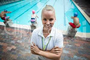Confident female instructor standing at poolside